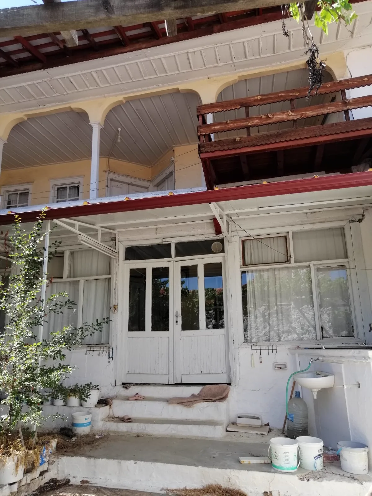Karamehmet'te kemerli ahşap hayatı ve camekânlı giriş kapısıyla geleneksel eski Muğla evi